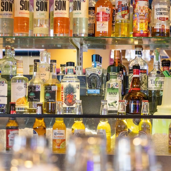 A well-stocked bar shelf with various liquor bottles, including vodkas, tequilas, and liqueurs.